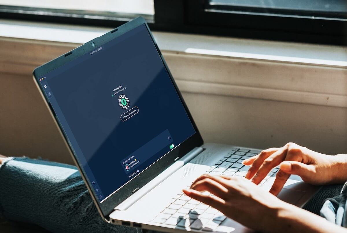 Closeup of a pair of hands working on a laptop. The screen has the Newshosting VPN on it and is connected to a secure server in London.